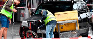 Ermittler untersuchen einen Rollstuhl. Der Geländewagen fuhr auch gegen den Briefkasten rechts und kam dort zum Stehen.