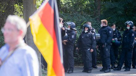 Polizisten stehen bei einer Kundgebung gegen die Corona-Beschränkungen auf der Straße des 17. Juni hinter einem Teilnehmer mit Deutschland-Flagge. Die Polizei hat die Veranstaltung kurz vor Ende doch noch aufgelöst.