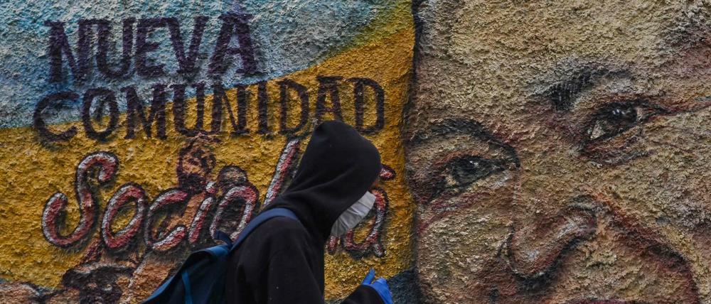 Relikte eines sozialistischen Scheiterns. Ein Mann mit Maske passiert im coronageplagten Caracas am 28. Juli 2020 ein Wandgemälde des verstorbenen Staatspräsidenten Hugo Chávez.