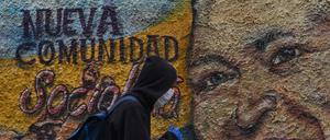 Relikte eines sozialistischen Scheiterns. Ein Mann mit Maske passiert im coronageplagten Caracas am 28. Juli 2020 ein Wandgemälde des verstorbenen Staatspräsidenten Hugo Chávez.