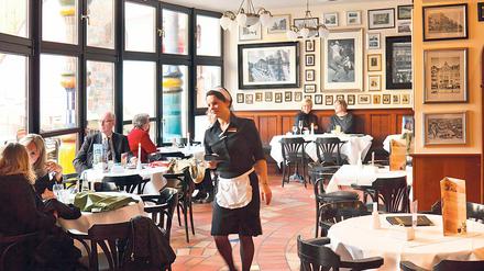 Eine junge Frau kellnert in einem Kaffeehaus.