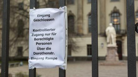 Zettel am Zaun vor dem Hauptgebäude der Humboldt-Universität, der Zugangsberechtigte auf einen Hintereingang verweist.