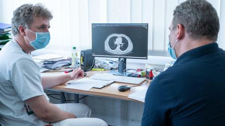Der Lungenfacharzt Torsten Blum (l.) erklärt einem Covid-19-Patienten auf einer Computertomographie die Spuren, die Covid-19 in der Lunge hinterlassen hat. 
