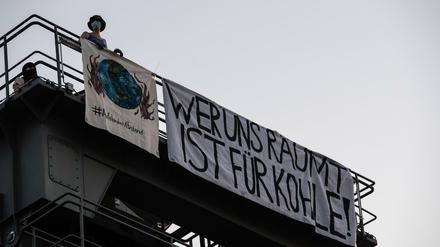 Eine Aktivistin der Umweltschutz-Initiative „Aufstand mit Abstand“ steht auf einem der Türme auf dem Gelände des Heizkraftwerks. 