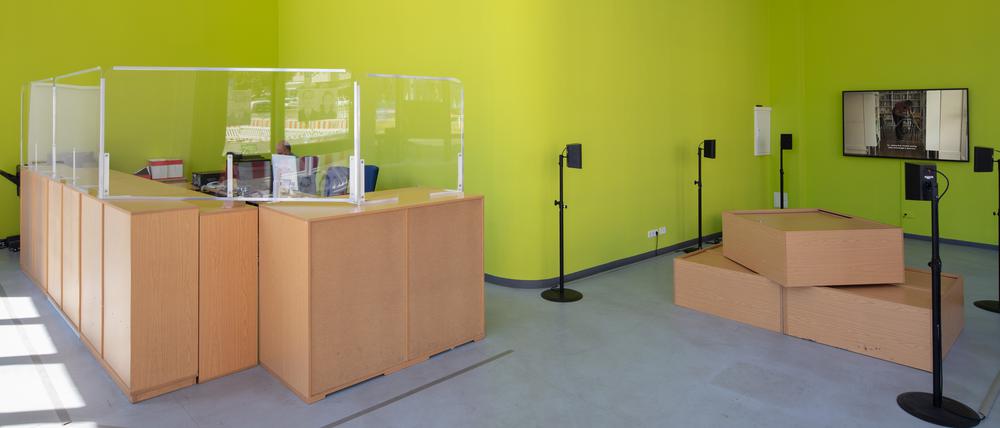 Unfreiwillige Improvisation. Links sind die Empfangstresen des Sozialamtes aufgestellt. Rechts eine Videoinstallation des Künstlers Burak Delier.