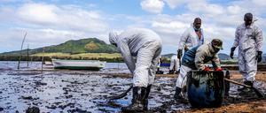 Helfer versuchen das Öl zu entsorgen. 