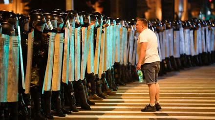 Ein Demonstrant spricht mit der Polizei, die mit Schutzschildern eine Straße blockiert. 