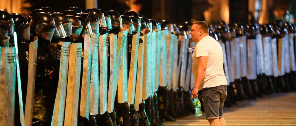 Ein Demonstrant spricht mit der Polizei, die mit Schutzschildern eine Straße blockiert. 