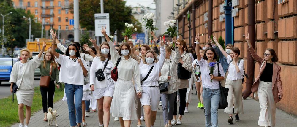 Demonstrantinnen in weißer Kleidung machen in Minsk Peace-Zeichen.