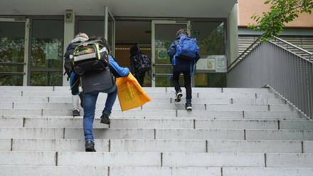 Schüler gehen die Außentreppe zum Eingang einer Schule hoch.