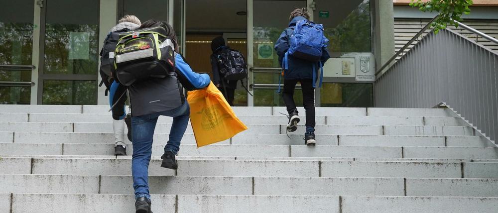 Schüler gehen die Außentreppe zum Eingang einer Schule hoch.