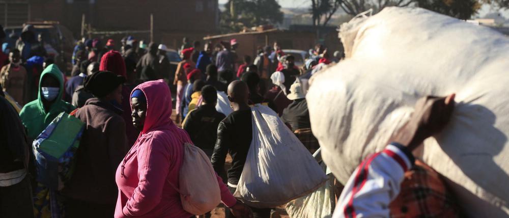 Menschen in Simbabwe warten an einem Busbahnhof. Präsident Mnangagwa kündigte strengere Maßnahmen an, um die steigende Zahl von Corona-Infektionen einzudämmen.