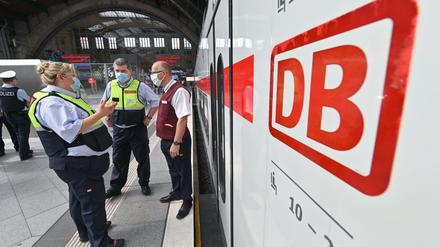 Bahnmitarbeiter kontrollieren das Tragen von Mund-Nasen-Bedeckungen.