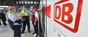 Bahnmitarbeiter kontrollieren das Tragen von Mund-Nasen-Bedeckungen.