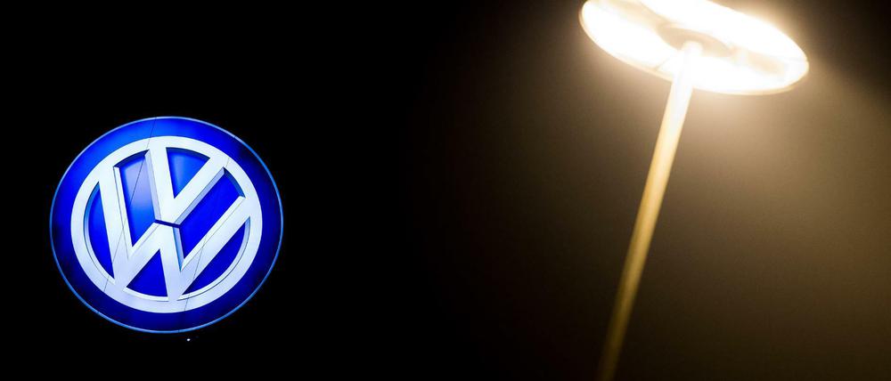 Das Volkswagen-Logo leuchtet an einem Werksgebäude. 