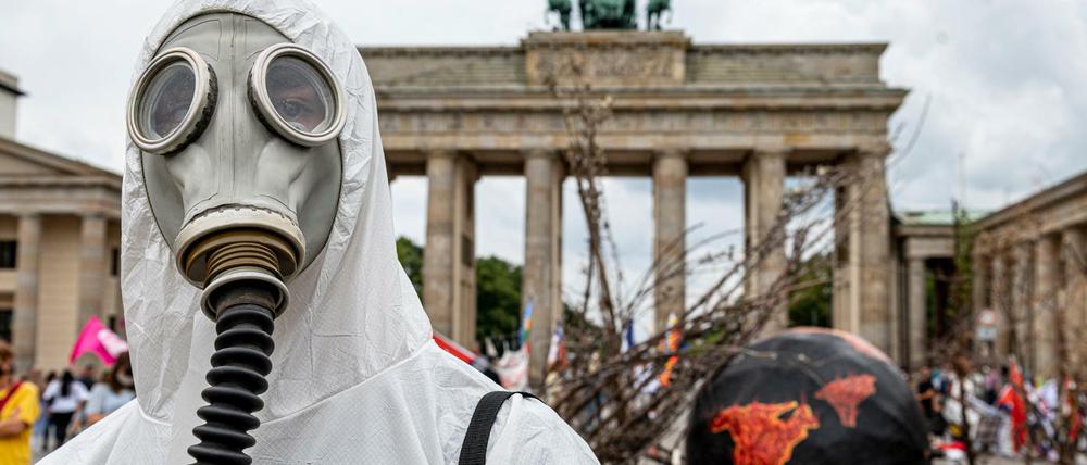 Ein Aktivist von Extinction Rebellion trägt zum "Global Earth Overshoot Day" vor dem Brandeburger Tor eine Gasmaske.