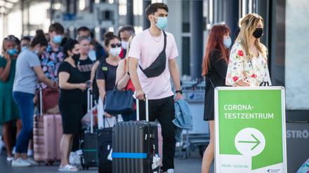 Reiserückkehrer stehen mit Mundschutz vor dem Corona-Testzentrum am Flughafen Stuttgart. 