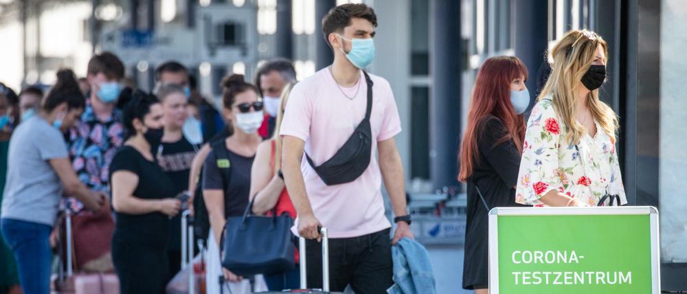 Reiserückkehrer stehen mit Mundschutz vor dem Corona-Testzentrum am Flughafen Stuttgart. 