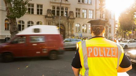 Eine Polizistin steht am frühen Morgen zu Schulbeginn vor einer Schule in Berlin.