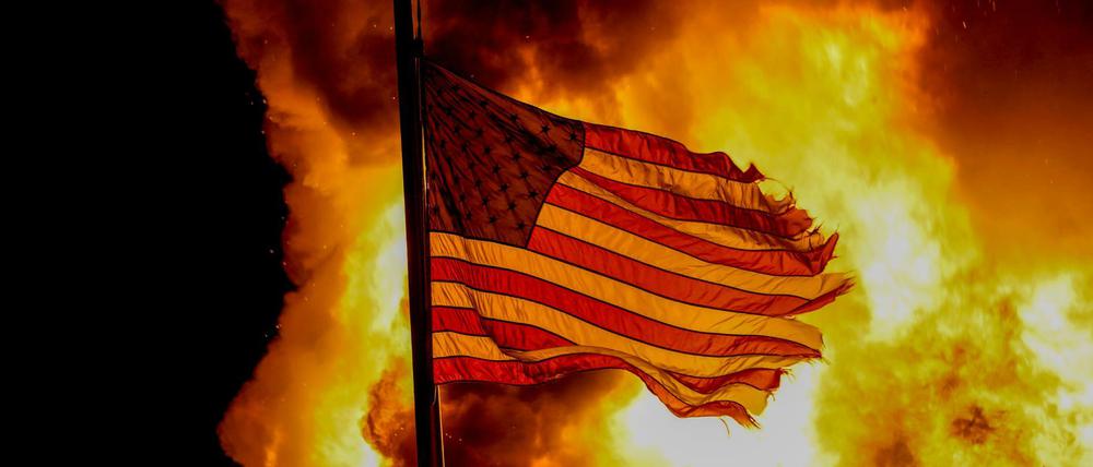 Proteste in Kenosha nach Schüssen auf einen Schwarzen: Eine US-Flagge weht über einem Gebäude, das in Brand stand.