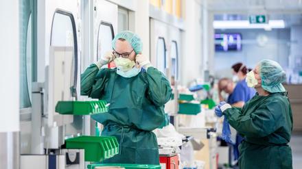 Vor einem Krankenzimmer auf einer Intensivstation bekleiden sich zwei Pflegepersonen mit Schutzkleidung.