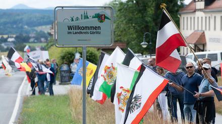 Rechte Teilnehmer eines Corona-Protests stehen mit Fahnen, darunter die Flagge des deutschen Kaiserreiches, an der Bundesstraße 96.