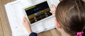 Eine Schülerin arbeitet zu Hause an ihrem Tablet mit einer Lern-App.