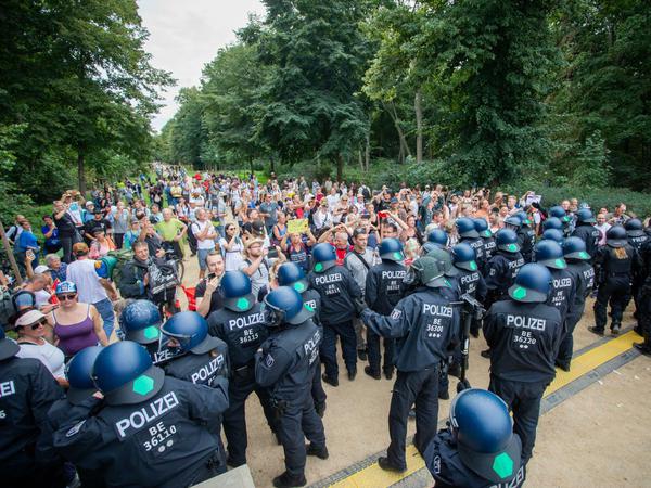 Polizisten drängen bei einem Protest gegen die Corona-Maßnahmen an der Siegessäule Menschen in den Tiergarten ab.