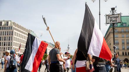 Personen mit Reichsflagge stehen am Folgetag eines Protests gegen die Corona-Maßnahmen auf dem Pariser Platz. 