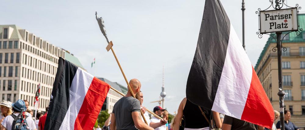 Personen mit Reichsflagge stehen am Folgetag eines Protests gegen die Corona-Maßnahmen auf dem Pariser Platz.