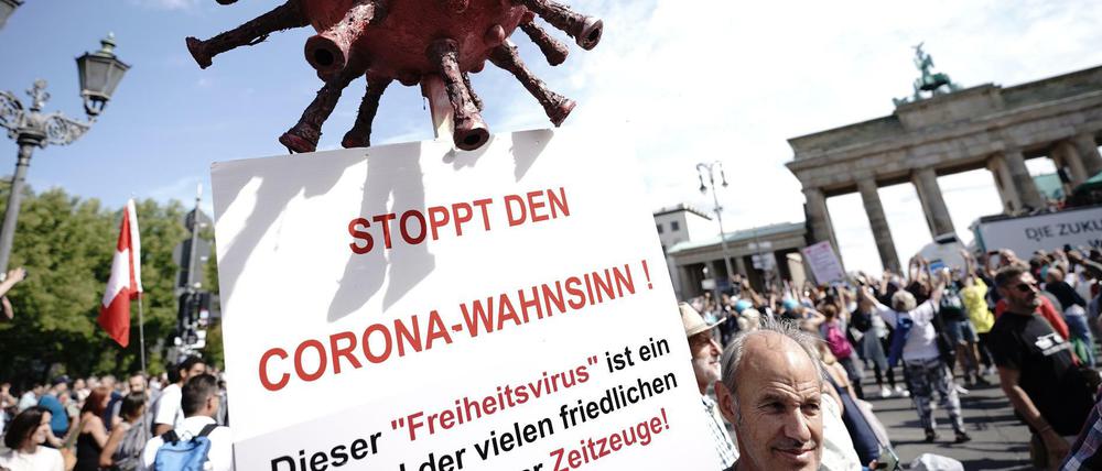Ein Demonstrant trägt ein Schild mit der Aufschrift "Stoppt den Corona-Wahnsinn".