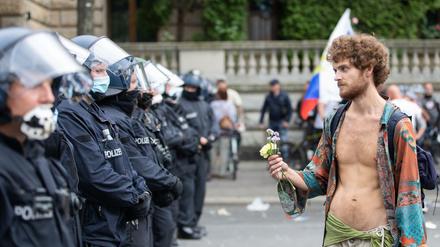 Ein Demonstrant hält bei einem Protest gegen die Corona-Maßnahmen vor der russischen Botschaft Blumen vor Polizisten.