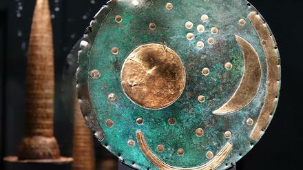 Nahaufnahme der Himmelsscheibe mit kegelförmigen Bronzehauben im Hintergrund.
