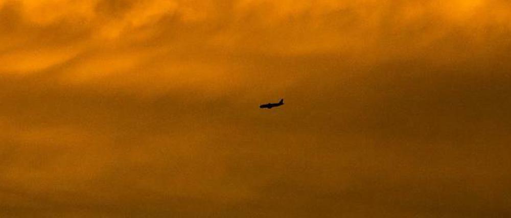 Romantisch. Ein Passagierflugzeug ist im Anflug auf den Flughafen Basel-Mulhouse als Silhouette vor dem vom Sonnenuntergang gefärbten Himmel zu sehen. 