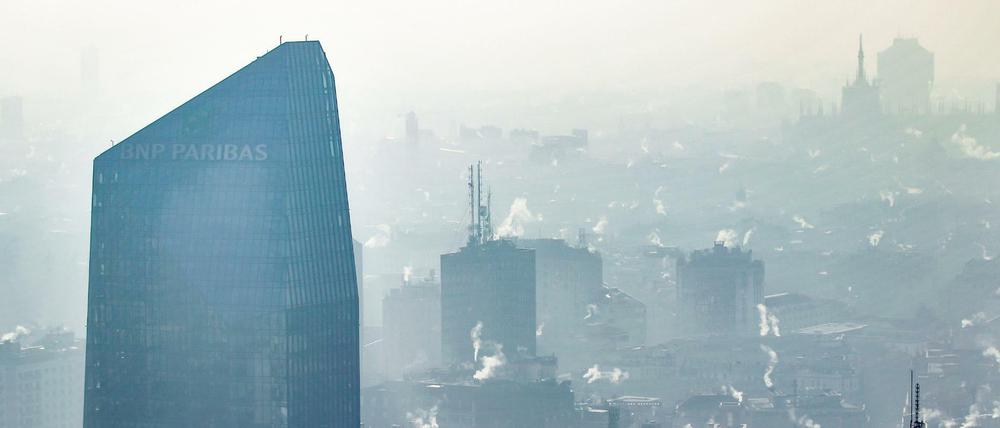 Weißer nebliger Rauch aus Schornsteinen hängt über der Innenstadt von Mailand.