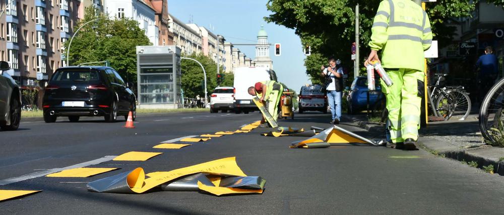 Bauarbeiter richten einen temporären Radweg auf der Frankfurter Allee ein.