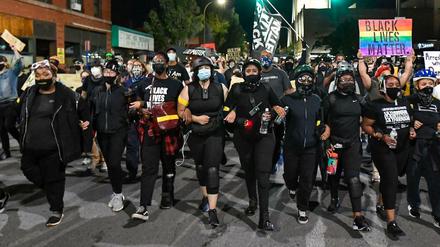 Demonstranten gehen untergehakt durch Rochester.
