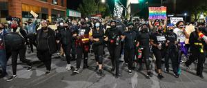 Demonstranten gehen untergehakt durch Rochester.