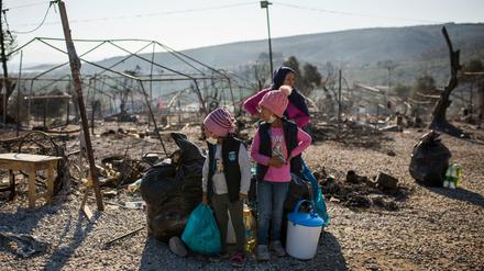 Eine Familie steht innerhalb des ausgebrannten Flüchtlingslagers Moria.