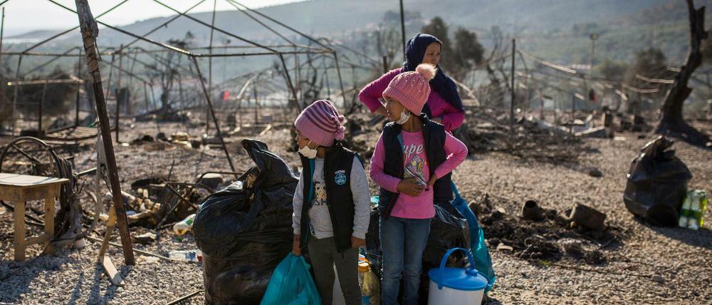 Eine Familie steht innerhalb des ausgebrannten Flüchtlingslagers Moria.