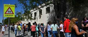 Menschen warten vor einer Schule in Madrid. 