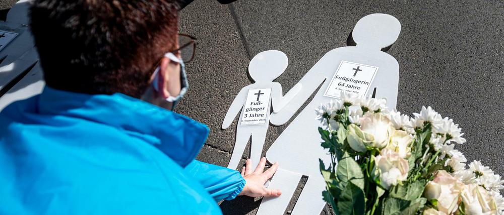 Eine Frau legt bei der Mahnwache zum Jahrestag des SUV-Unfalls in der Invalidenstraße Blumen auf den Boden.