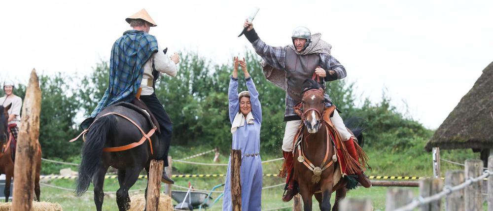 Kostümierte Reiter und Reiterinnen führen einen Schaukampf auf.