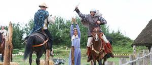 Kostümierte Reiter und Reiterinnen führen einen Schaukampf auf.