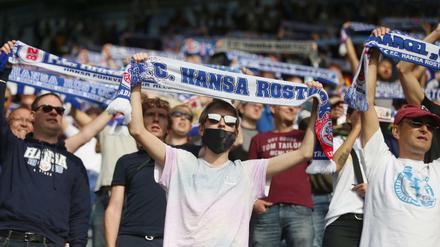 Fußballfans stehen auf den Tribünen im Ostseestadion. 
