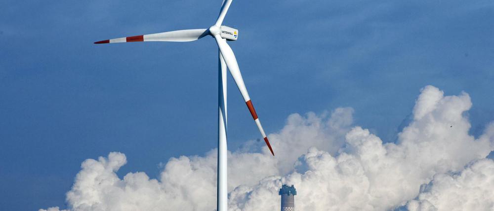 Eine Windkraftanlage vor den qualmenden Kühltürmen des Braunkohlekraftwerks Jänschwalde. 