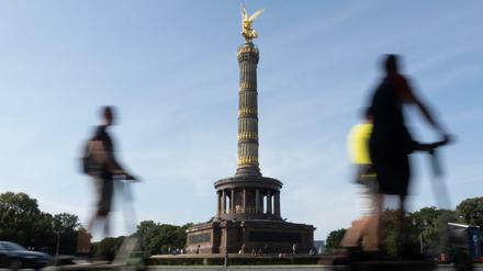 Sommerwetter in Berlin: Mit E-Scootern fahren drei Männer am Großen Stern an der Siegessäule vorbei.