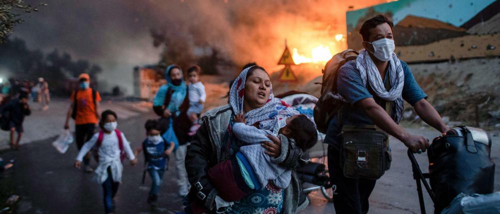 Migranten fliehen vor einem erneuten Feuers mit ihren Habseligkeiten aus dem Flüchtlingslager Moria