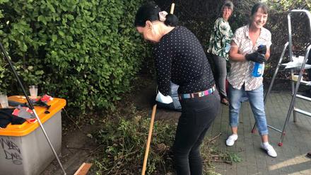 Ehrenamtliche putzen im Treptower Kunger-Kiez Garten und Hof.