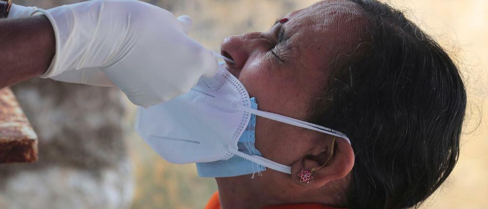Ein medizinischer Mitarbeiter entnimmt einer Frau einen Nasenabstrich für einen Corona-Test. Indien ist das weltweit am zweitstärksten von der Pandemie betroffene Land. 